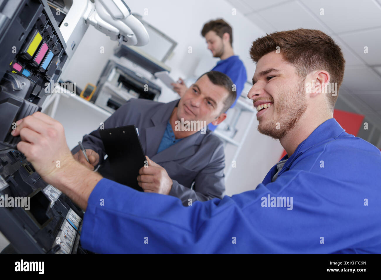 apprentice repairing printer with teacher monitoring Stock Photo