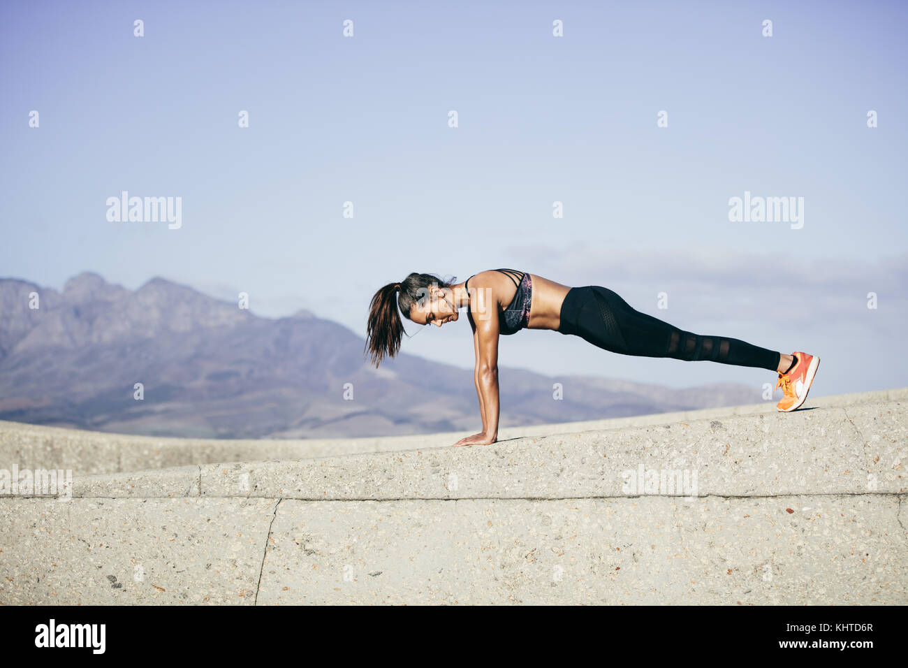 Tough young woman doing pushups outdoors. fitness female exercising in morning. Stock Photo
