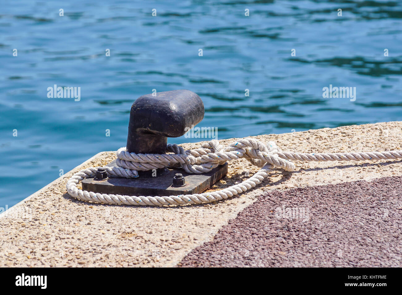Old metal dock mooring pole with ring and rope for securing fishing