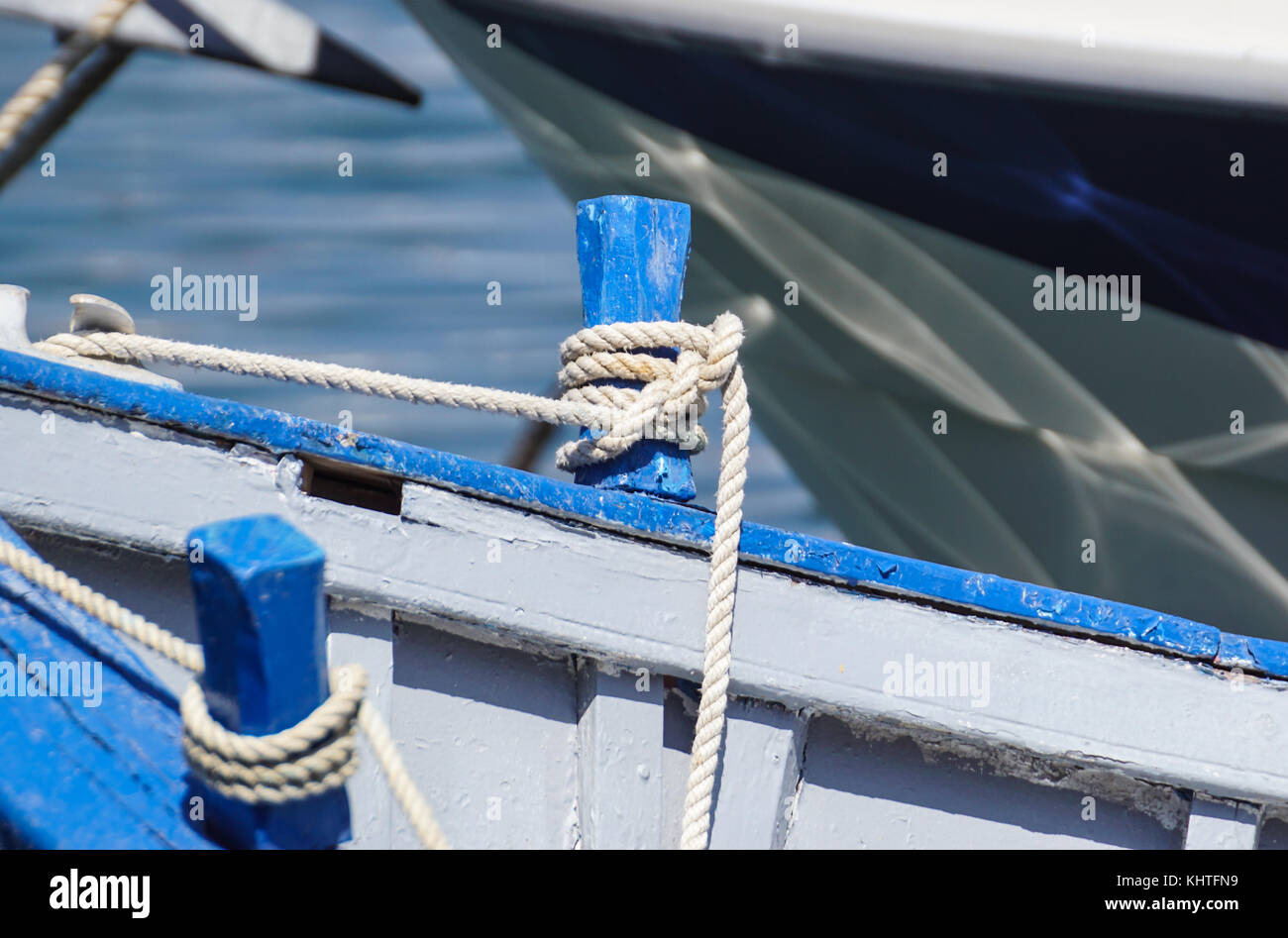 Knotted blue rope laying over the side of a old wood boat Stock Photo