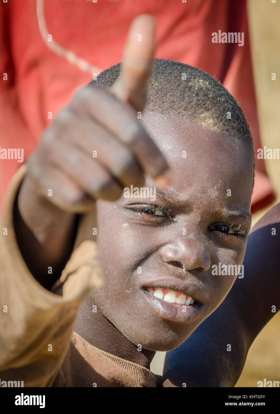 CAOTINHA, BENGUELA, ANGOLA - MAY 11 2014: Portrait of unidentified African boy with dirty face showing a thumbs up sign Stock Photo