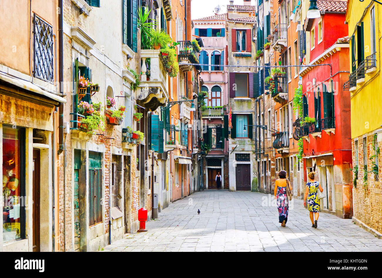 View of the colorful Venetian houses with some visitors walking by in Venice, Italy. Stock Photo