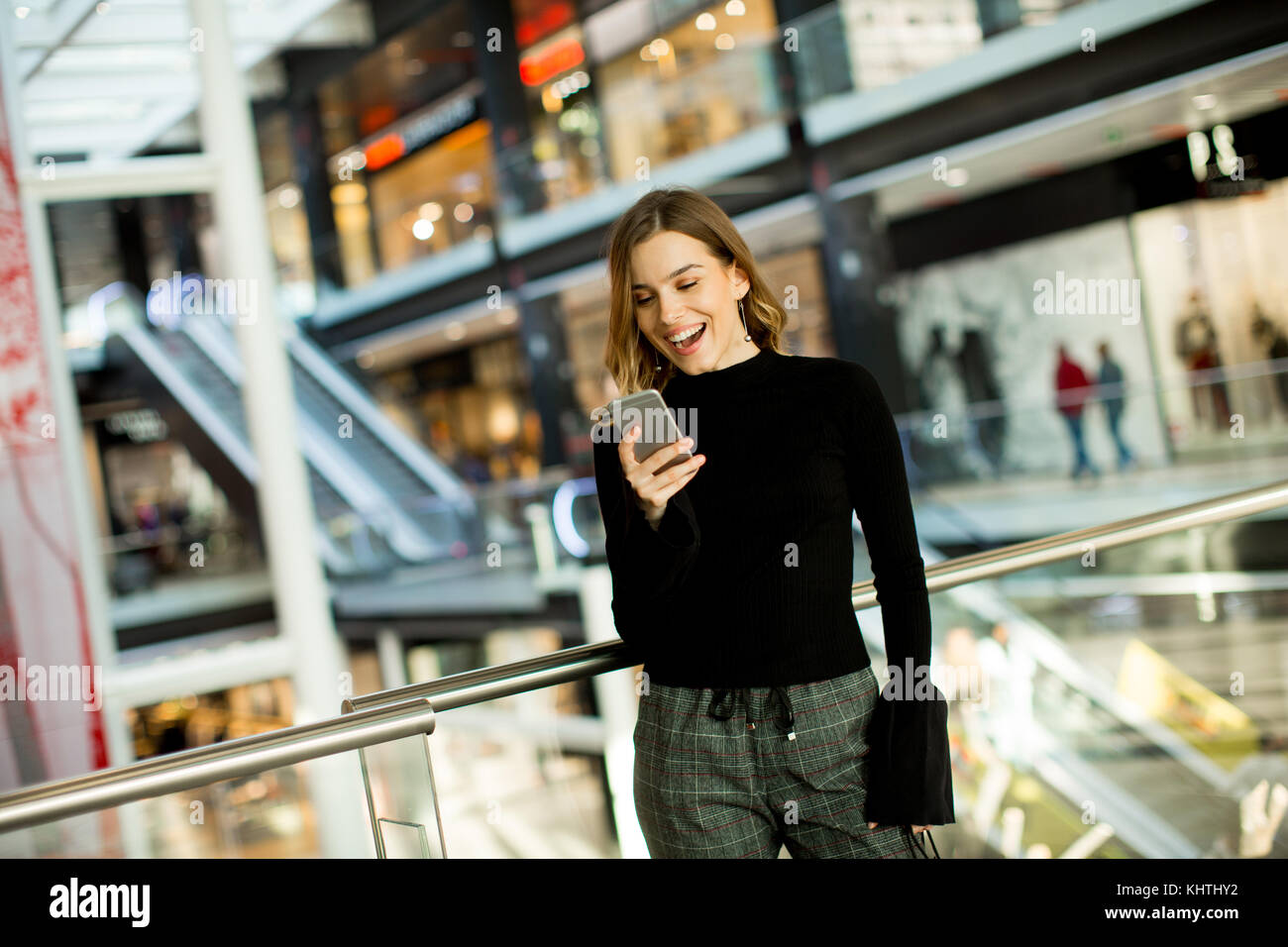 Portrait of lovely young woman looking on mobile phone in shopping center Stock Photo