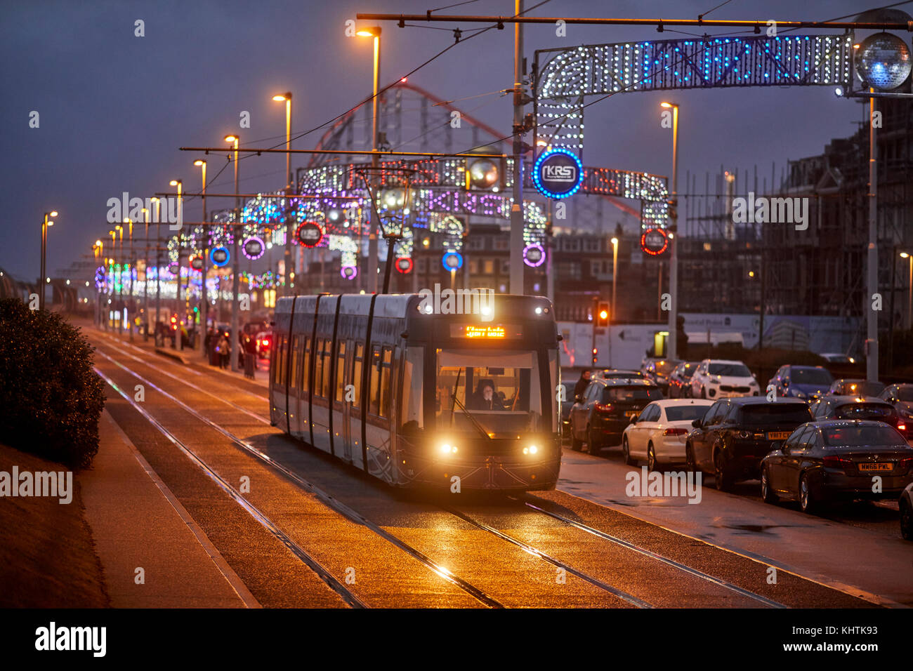 Blackpool tram running along the promenade at night with the Pleasure beach behind, in Lancashire Stock Photo