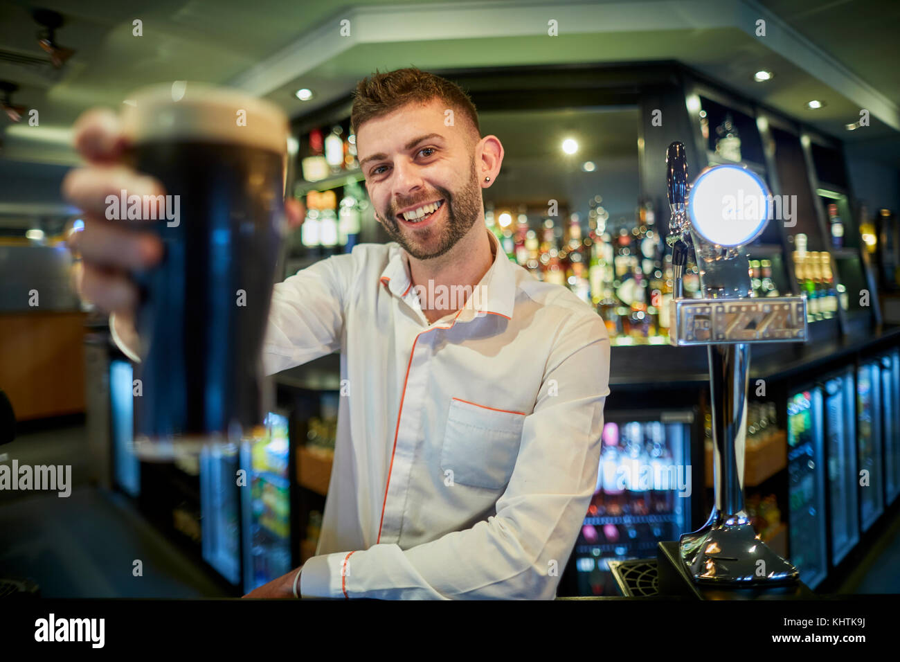 A barman holing a pint at Marston's The Old Duke pub in Southport in Merseyside Stock Photo