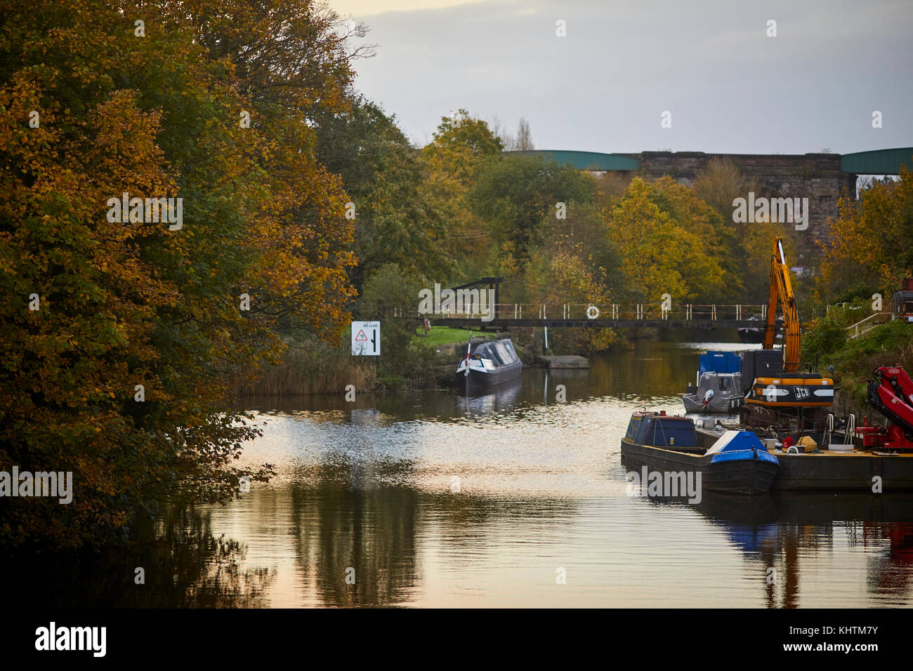 Canal boats floating on the River Weaver with golden autumn trees in the landscape, Northwich in Cheshire Stock Photo
