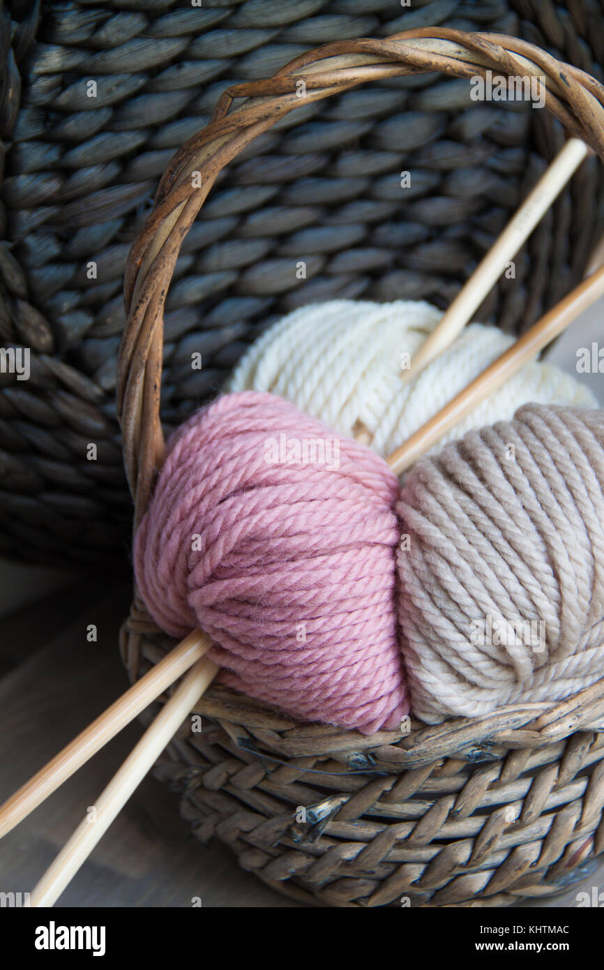 Yarn balls with knitting needles in the basket on the wooden background ...