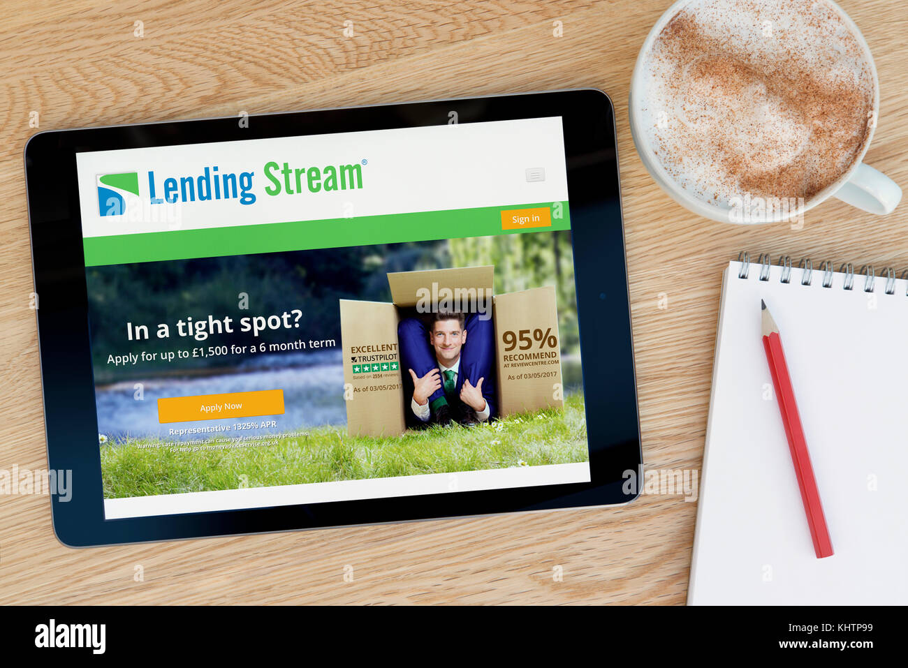 The Lending Stream website on an iPad tablet device which rests on a wooden table beside a notepad and pencil and a cup of coffee (Editorial only) Stock Photo