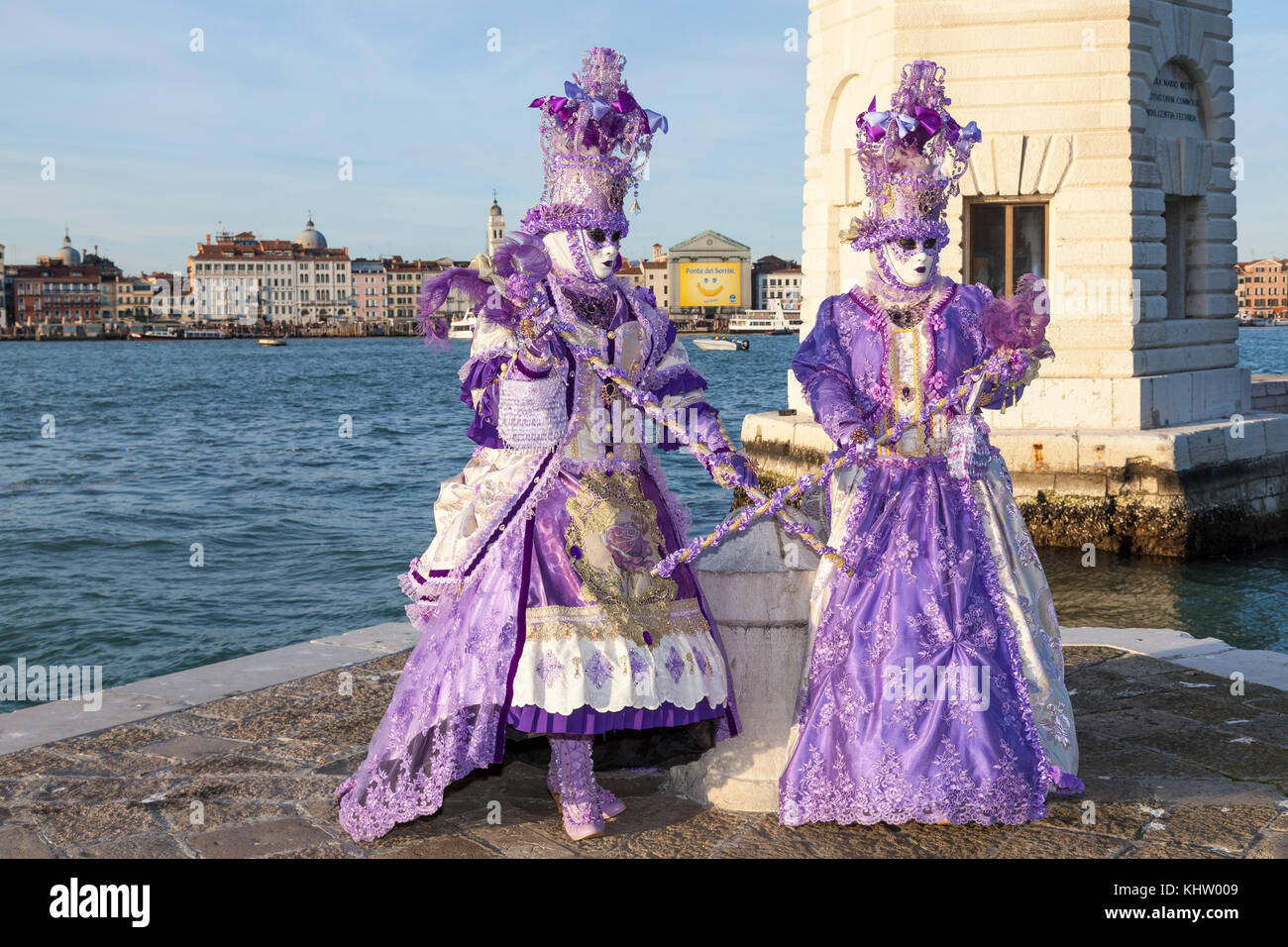 Venice Carnival 2017, Veneto, Italy, Two women in purple posing in front of the lighthouse on San Giorgio Maggiore with copy space Stock Photo
