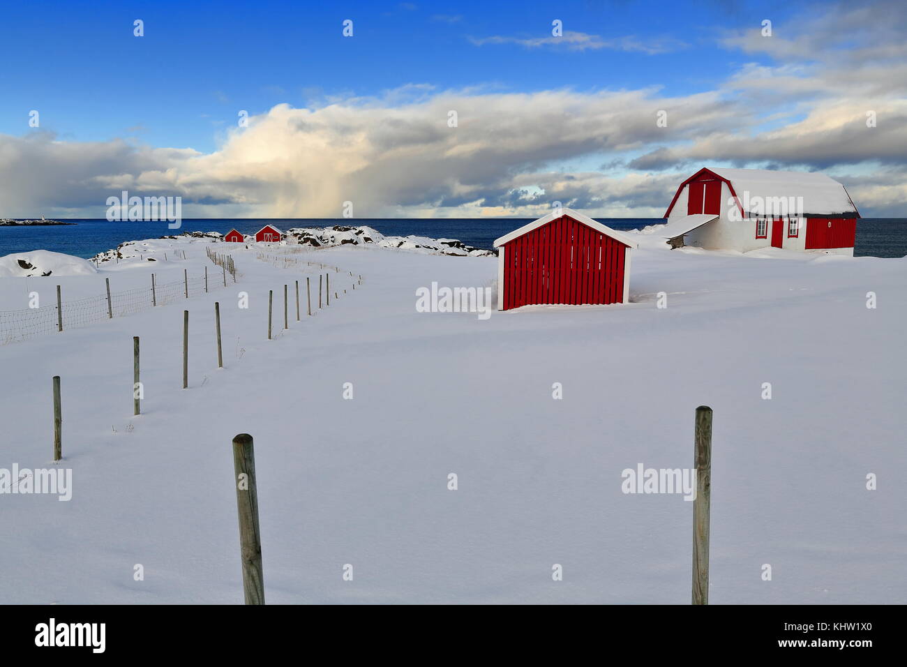 Red-white traditional fishing huts-robuer now for tourist use beside Fv 862 road on the N.shore of Gimsoya island under thick snow blanket near Hovsvi Stock Photo