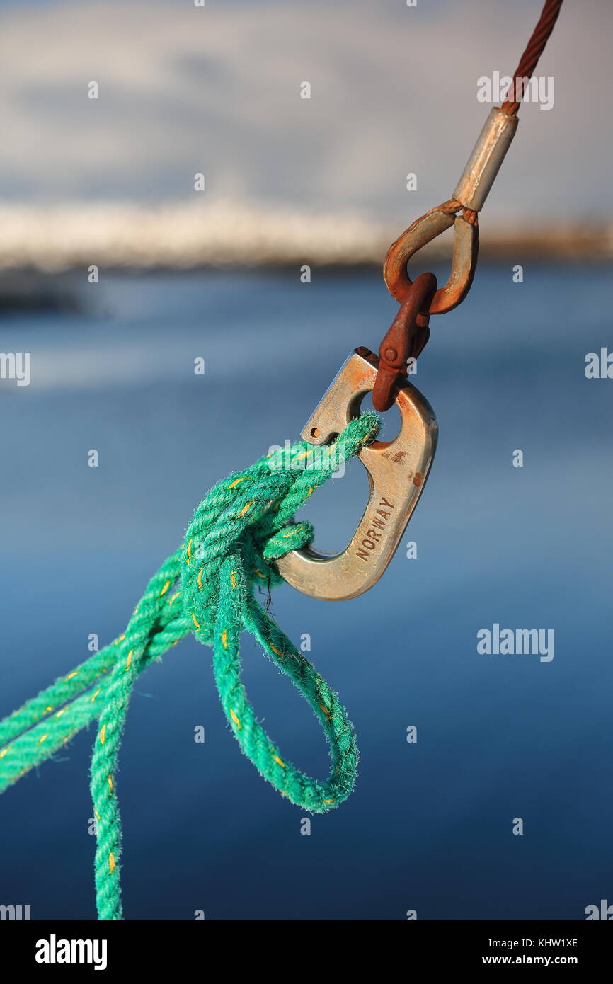 Hovsund fishing port-line of oxidized shackles tied up with green rope and boating knot in a fishing ship unloading its catch. Hov village of Vagan ko Stock Photo