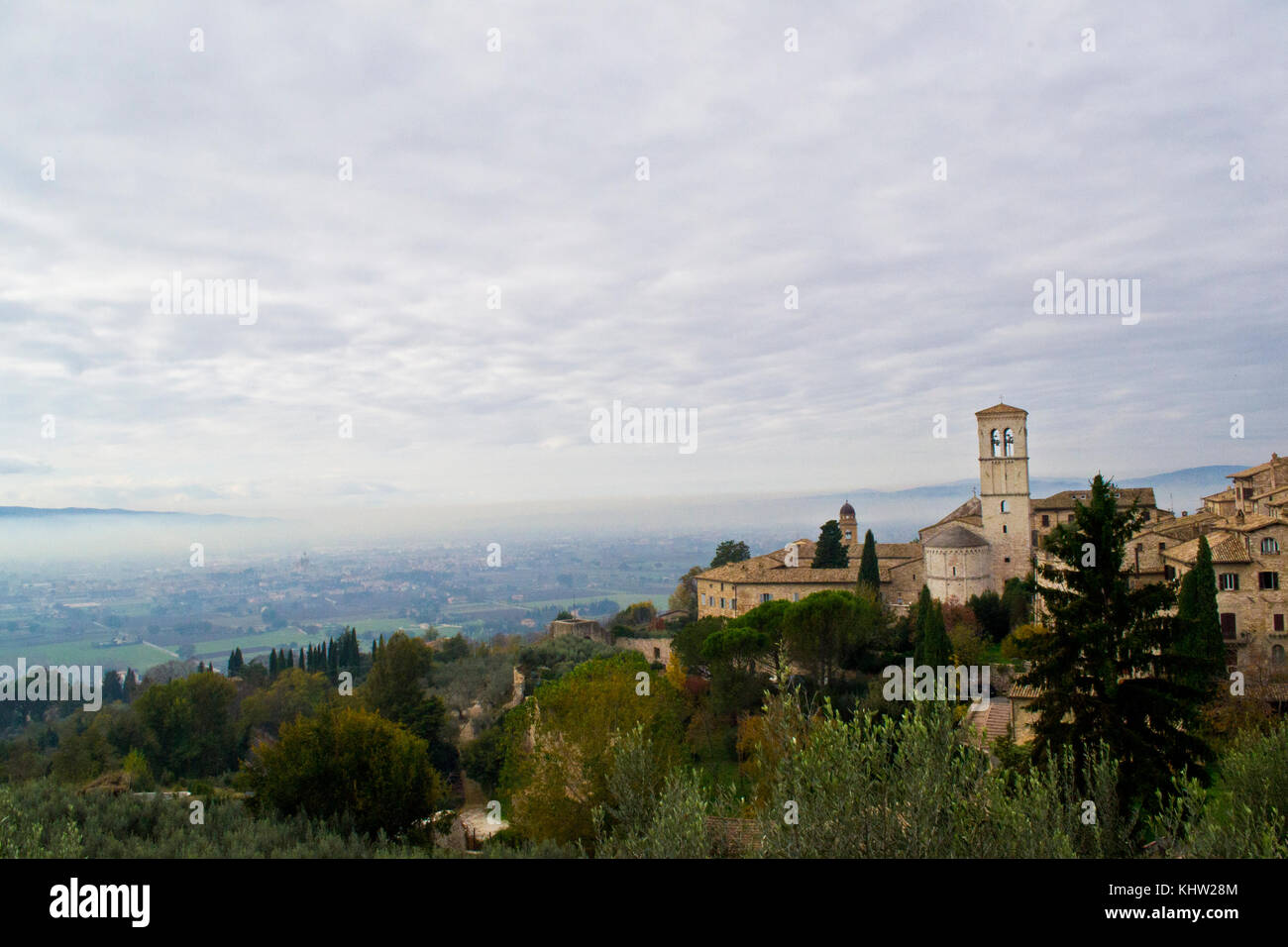 Assisi. View from Piazza Santa Chiara during a november misty day. On background shrine of Santa Maria degli Angeli known as Porziuncola Stock Photo