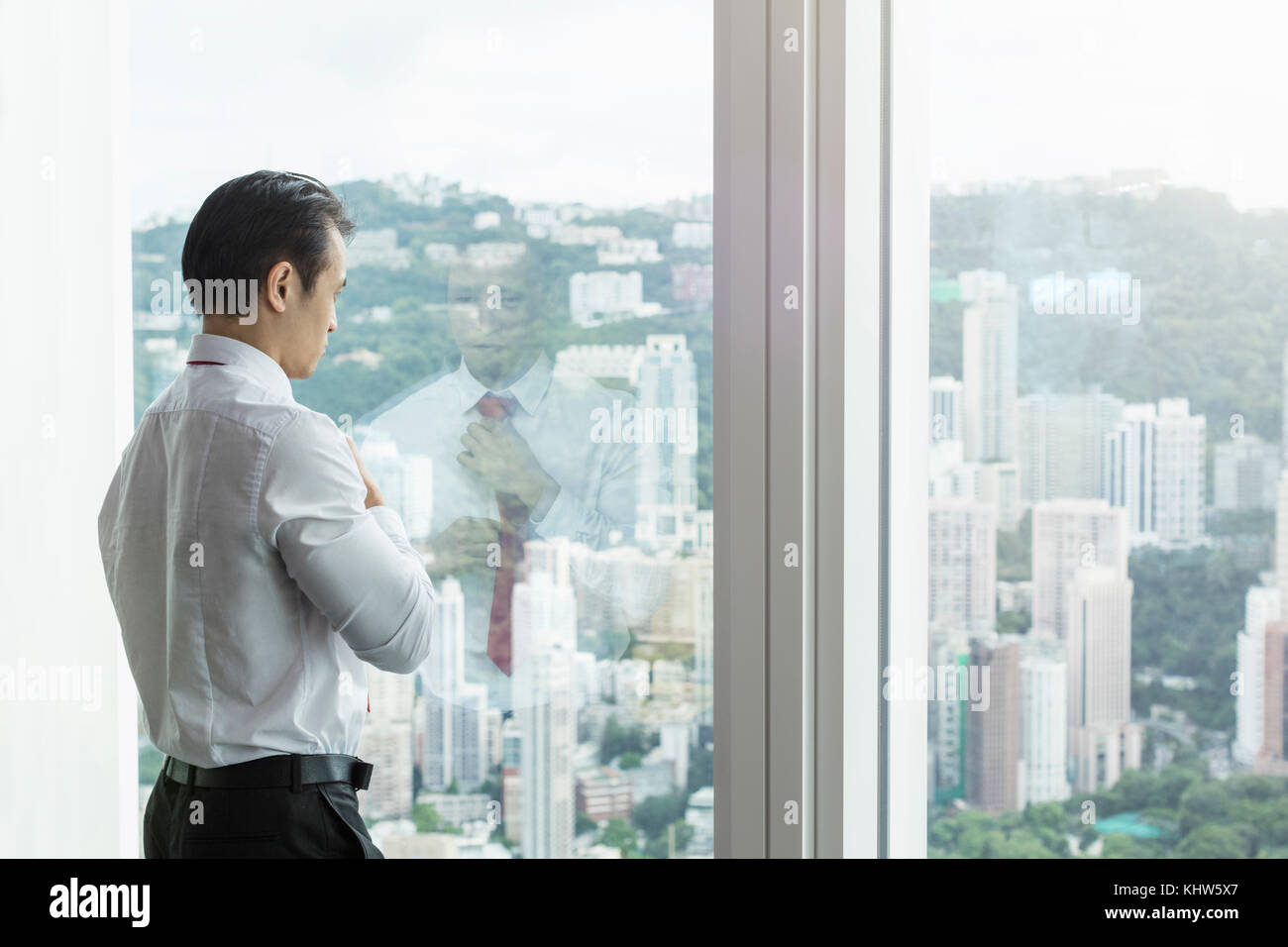 Man looking through window at cityscape stock photo - OFFSET