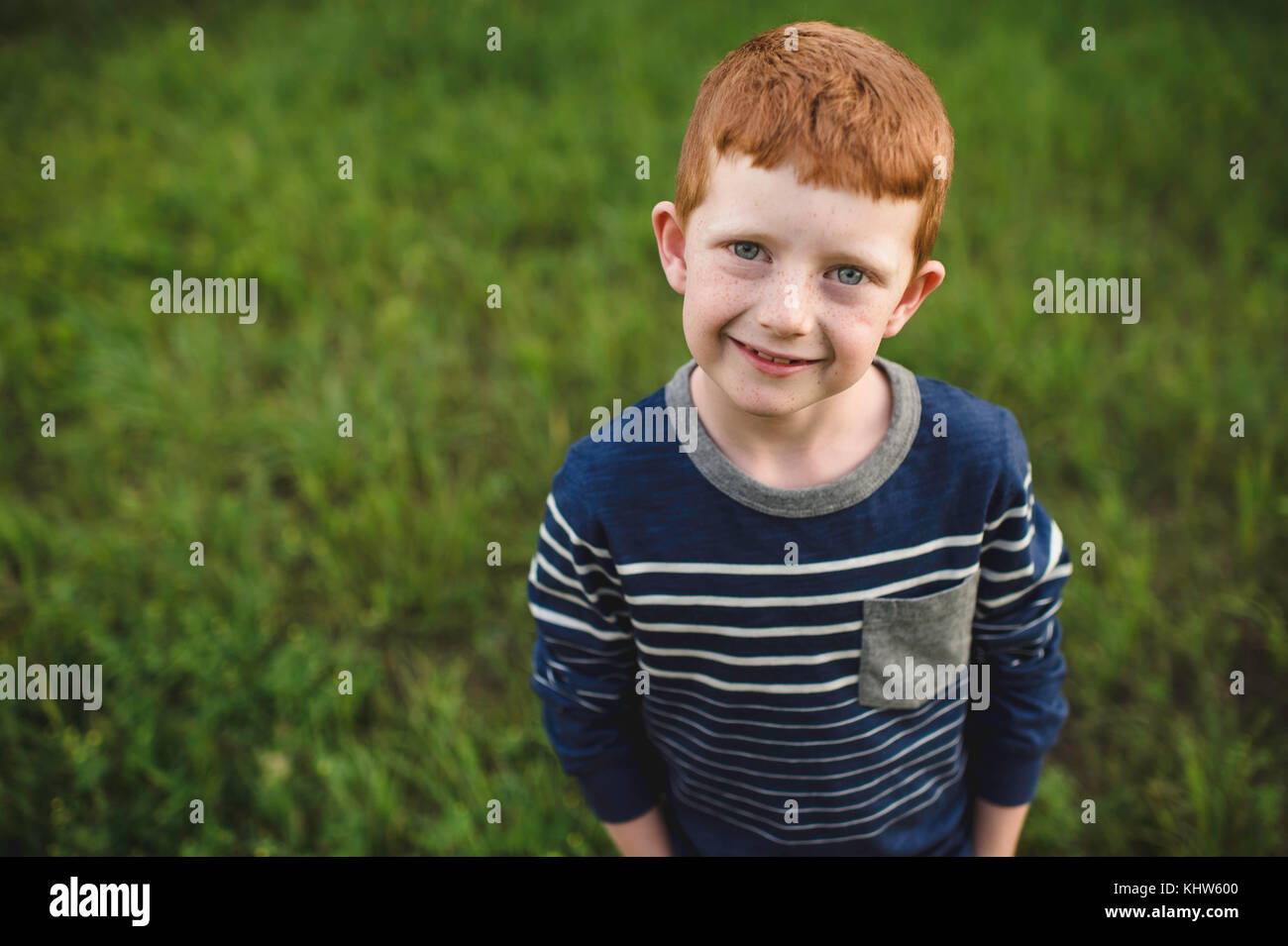 Portrait of red haired boy standing on grass Stock Photo