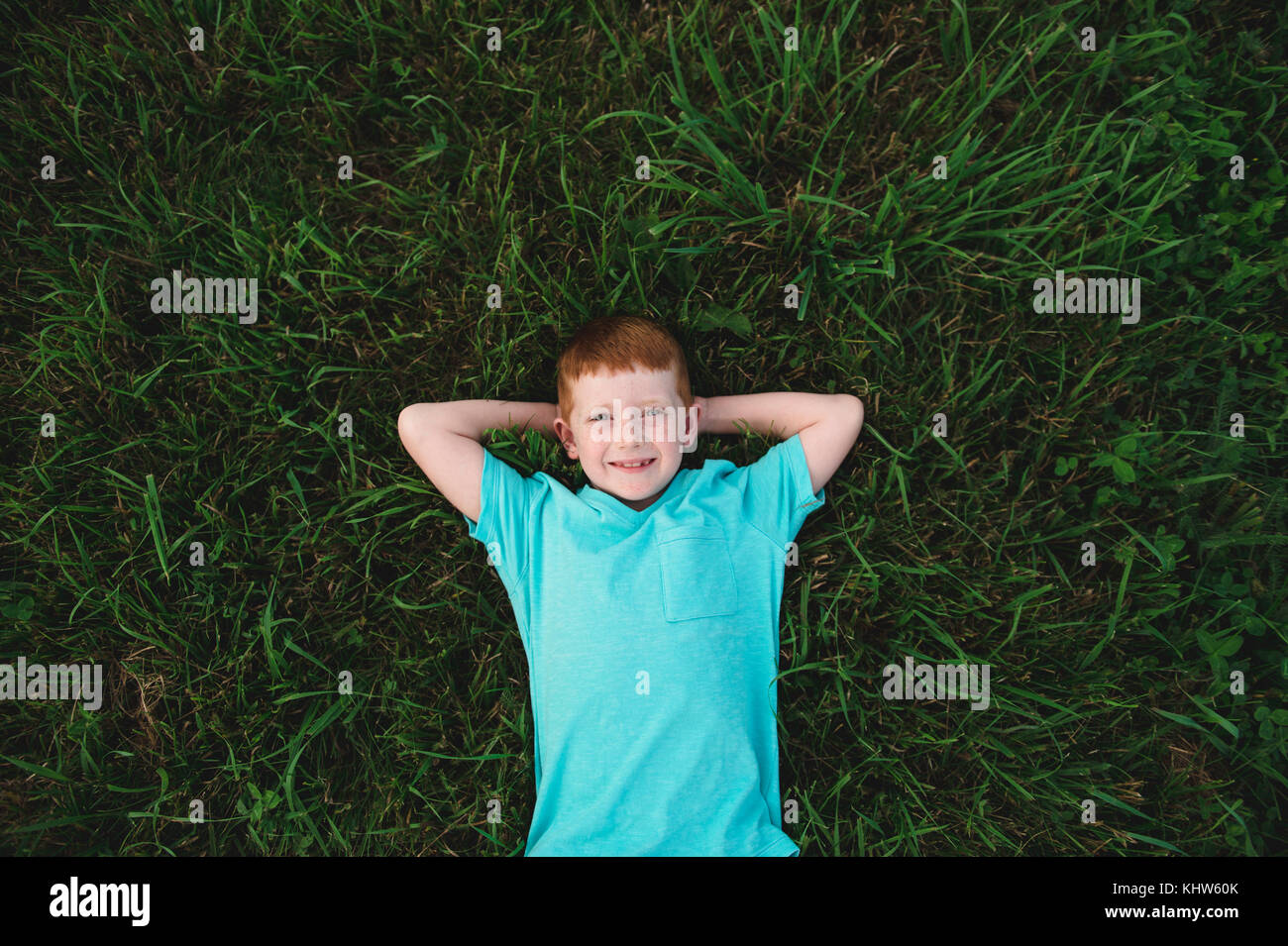 Overhead portrait of red haired boy lying on grass Stock Photo