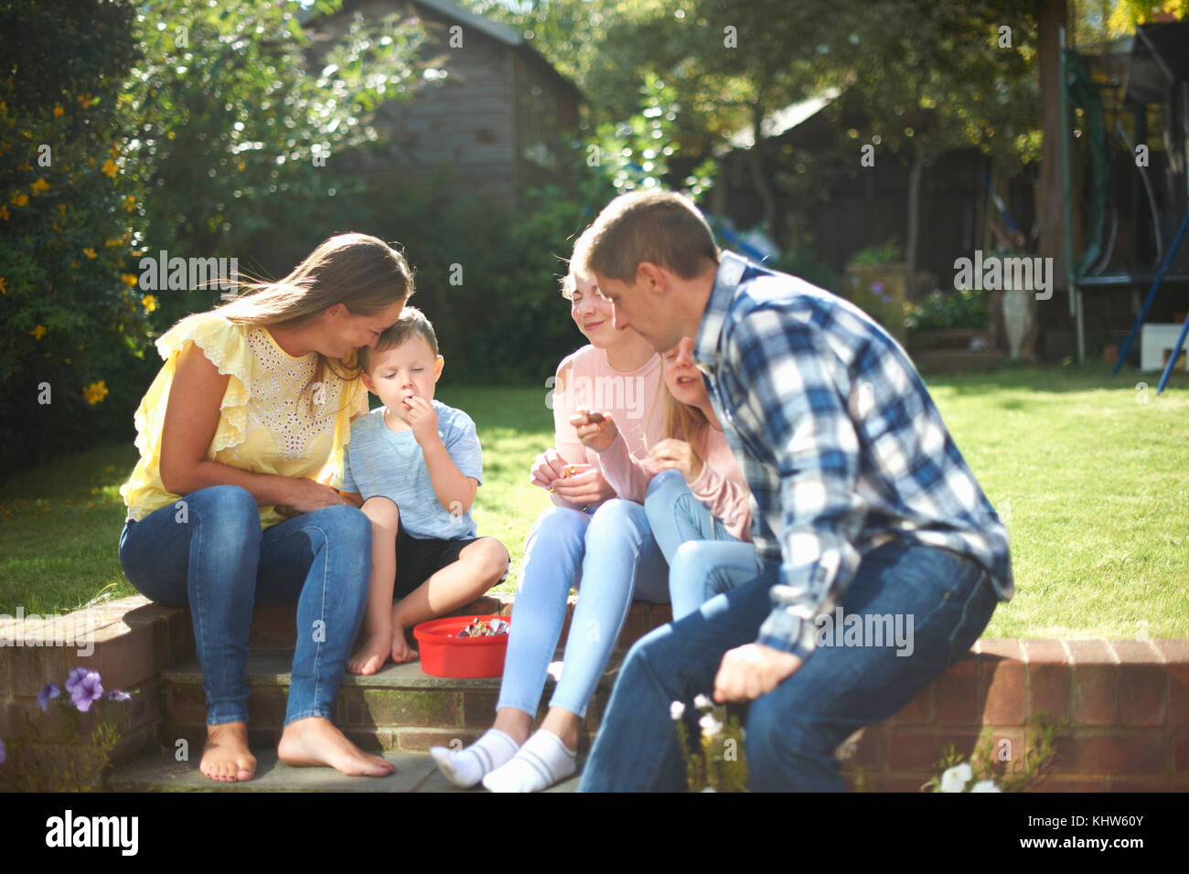 Family, sitting in garden, eating sweets Stock Photo