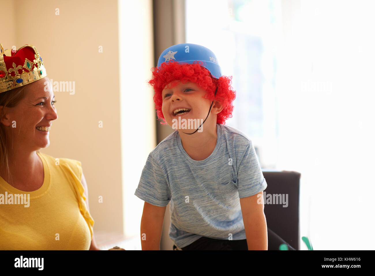 Mother and son playing dress up, wearing funny hats, laughing Stock Photo