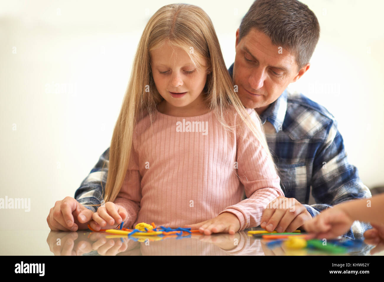 Father son and daughter, sitting at table, playing with modelling clay Stock Photo