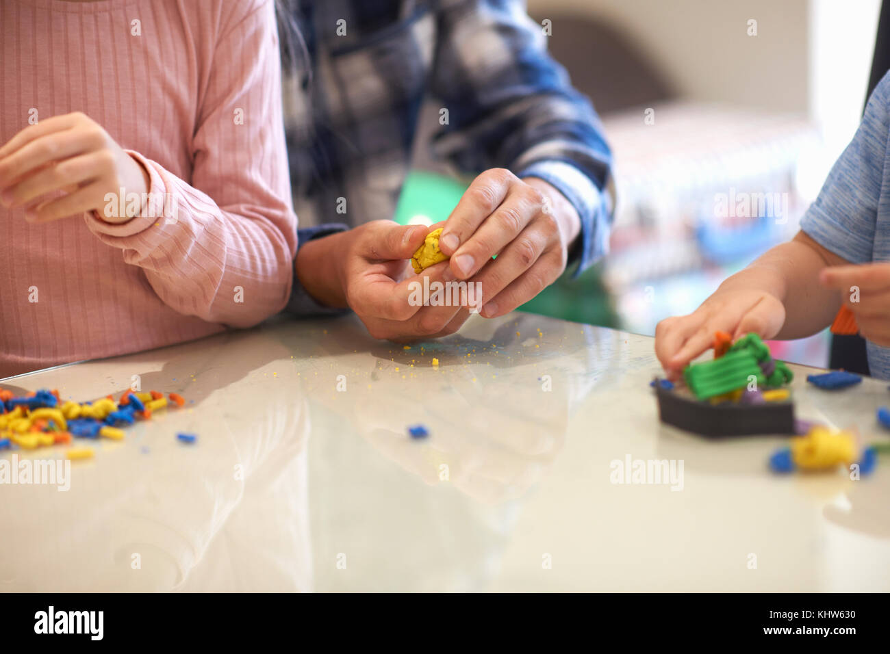 Father, son and daughter, sitting at table, playing with modelling clay, mid section Stock Photo