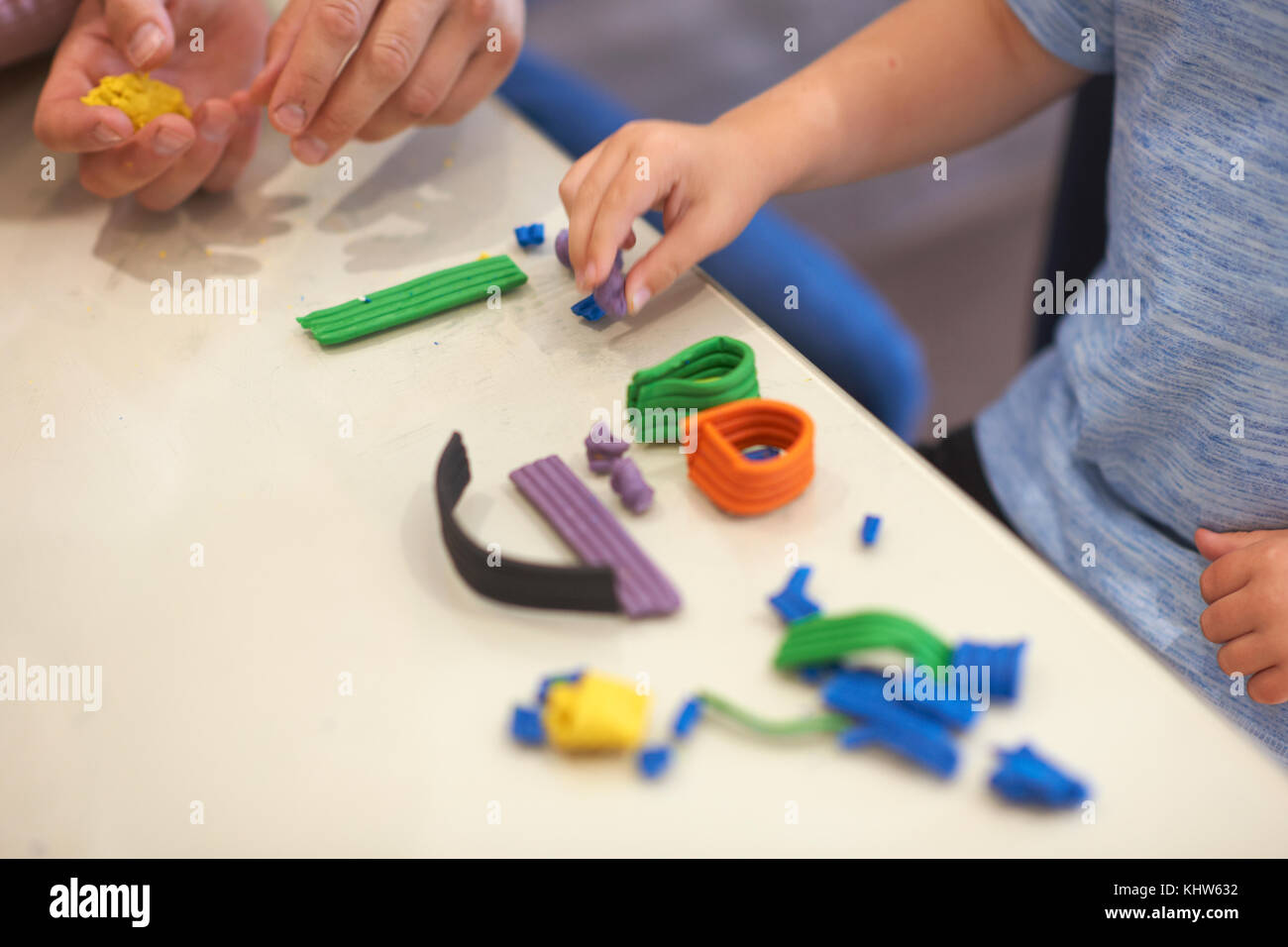 Father and son, sitting at table, playing with modelling clay, close-up Stock Photo