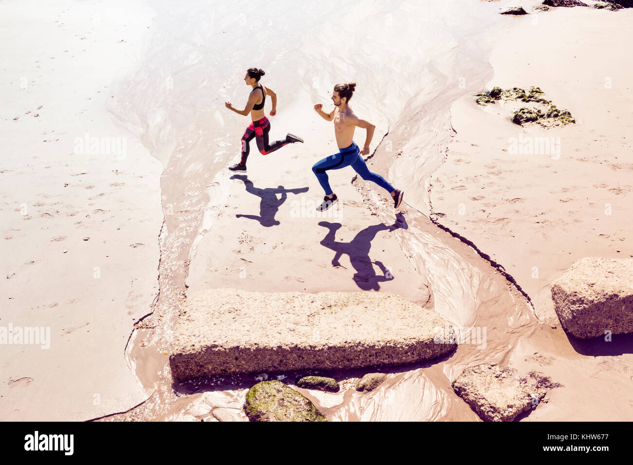 Young man and woman running along beach, elevated view Stock Photo