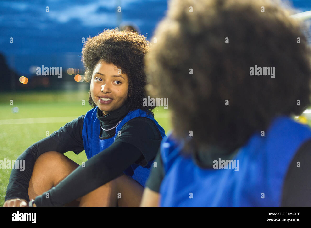 Female football players sitting by field, Hackney, East London, UK