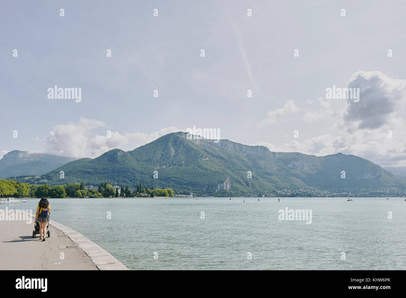 Rear view of woman strolling with pushchair waterfront at Lake Annecy, Annecy, Auvergne-Rhone-Alpes, France Stock Photo