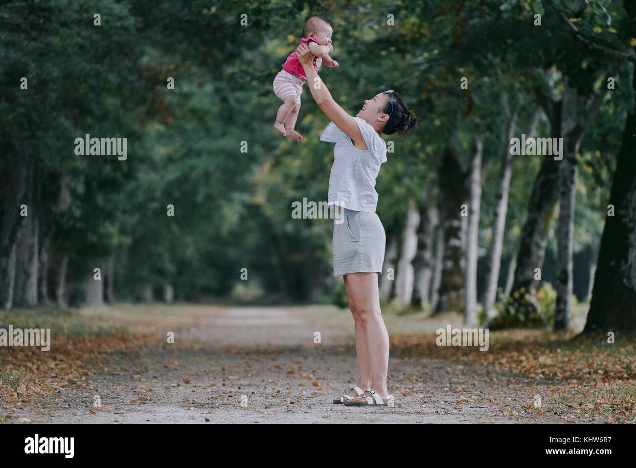 Woman holding up baby daughter in tree lined park, Chenonceaux, Loire Valley, France Stock Photo