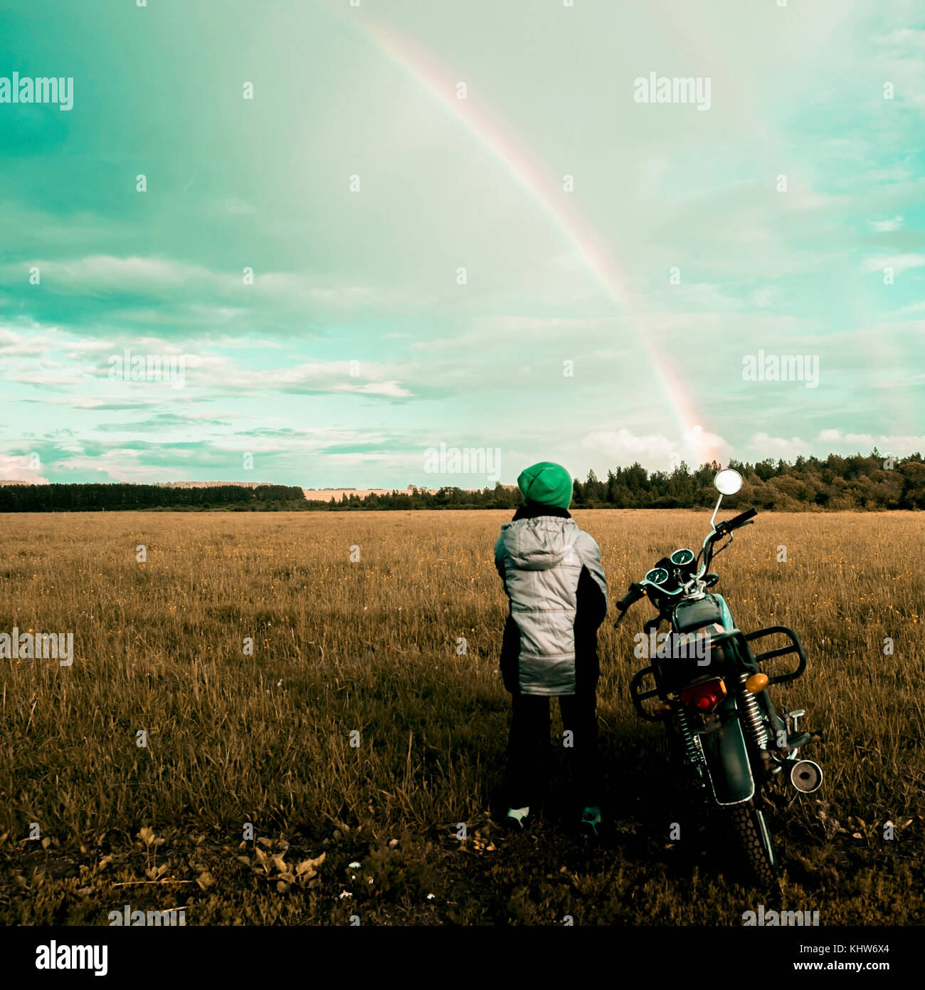 Boy by motorbike looking at rainbow, Ural, Sverdlovsk, Russia Stock Photo