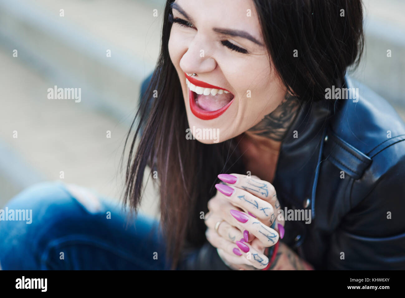 Portrait of young woman laughing, tattoos on neck and hand Stock Photo