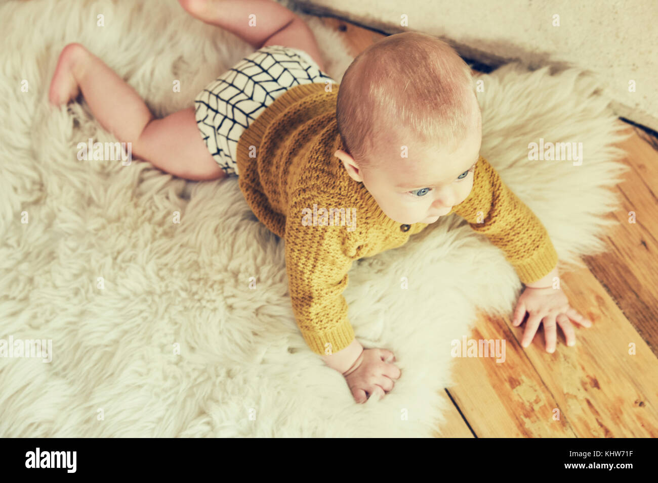 Overhead view of baby boy lying on sheepskin rug Stock Photo