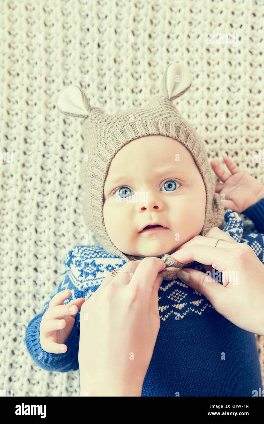 Mother's hands fastening baby sons knitted hat with ears Stock Photo