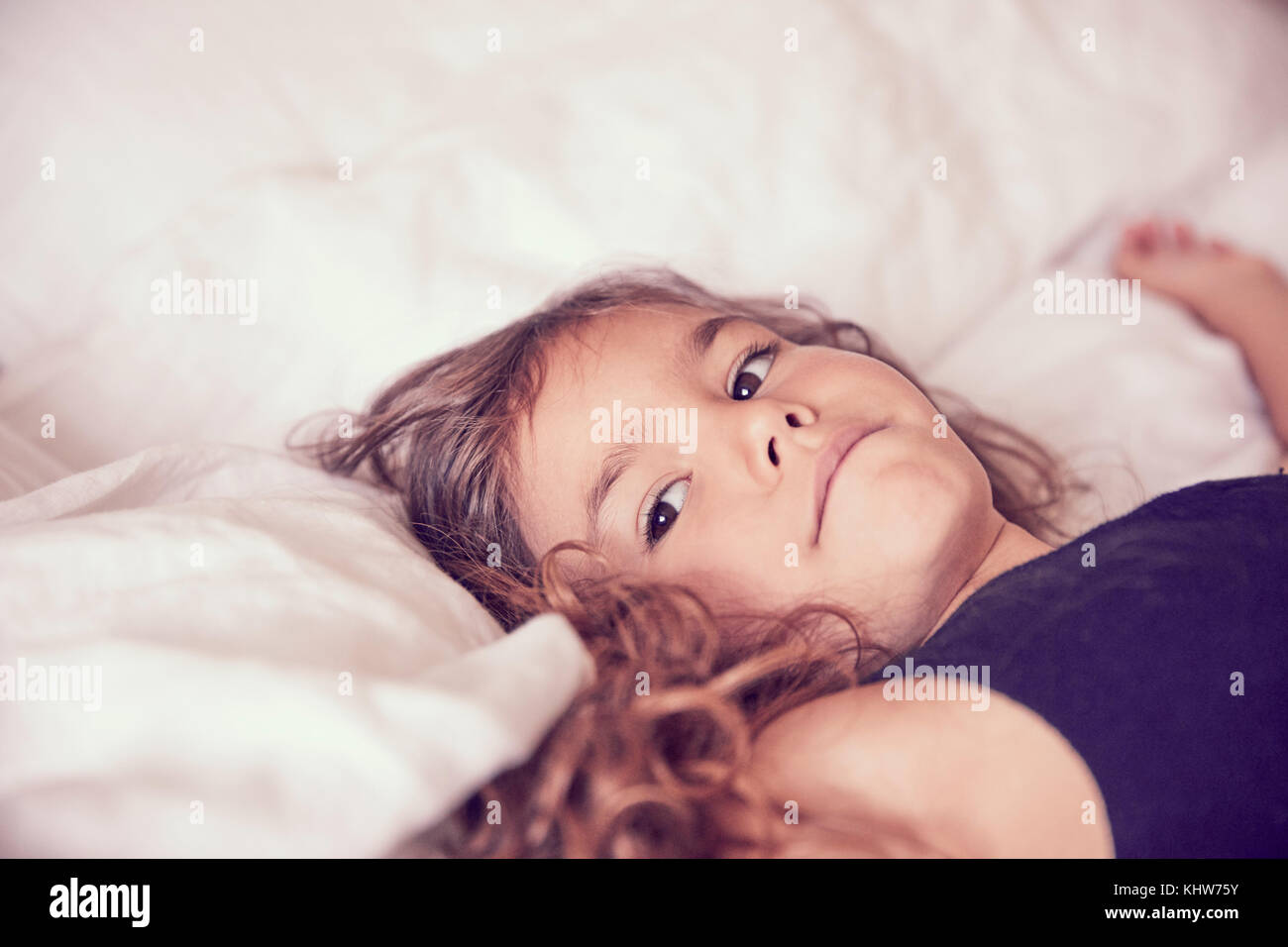 Young girl lying on bed, pensive expressions Stock Photo