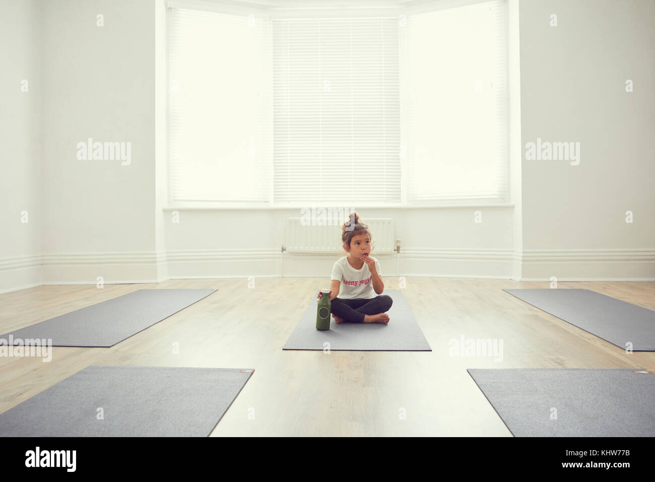 Young girl in yoga studio, sitting on yoga mat Stock Photo