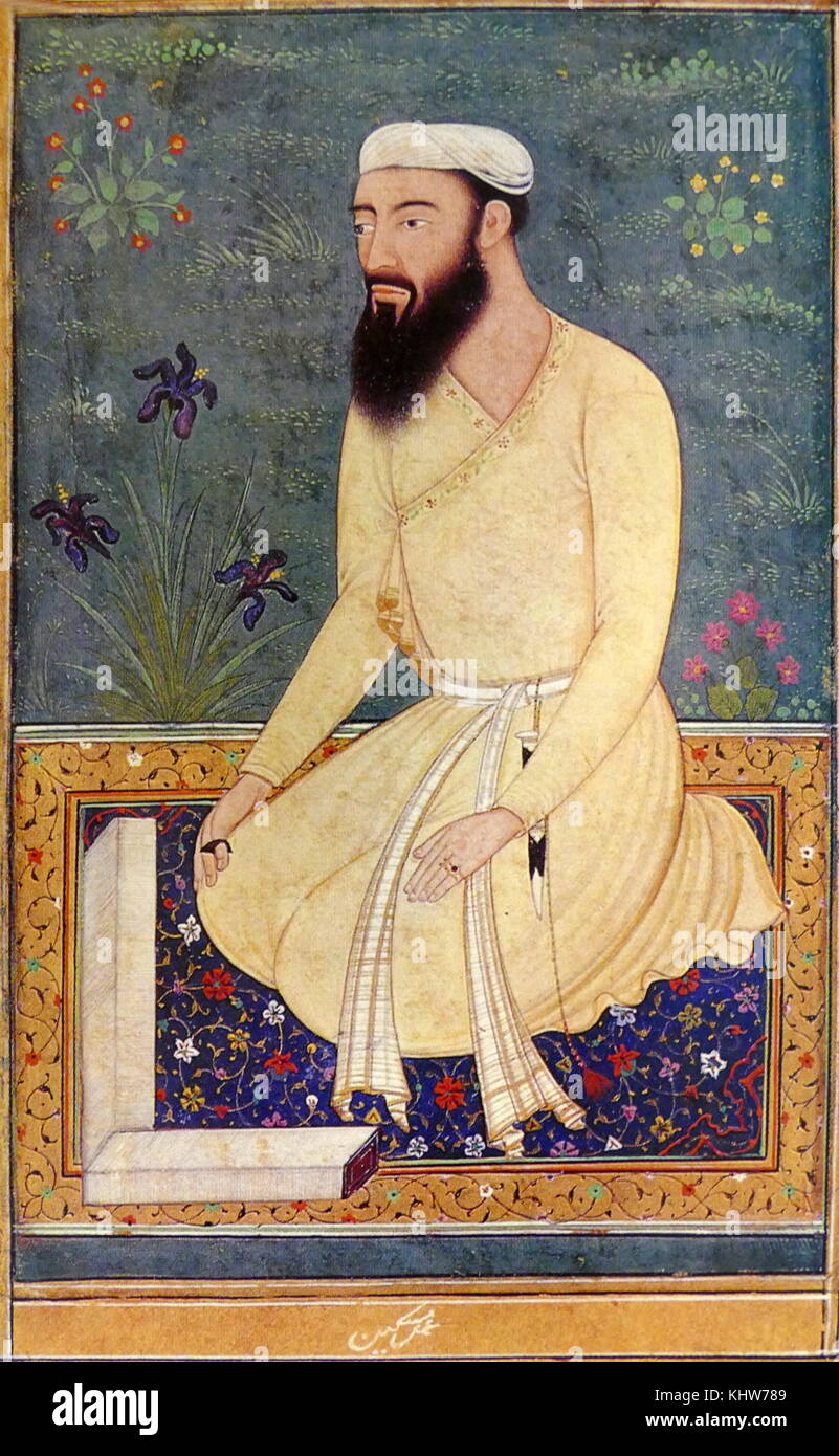 Portrait of a learned Mughal courtier. He is kneeling on a richly coloured carpet with the pages of unbound book spread out before him; he has a full black beard and moustache and is dressed in a simple white turban and plain yellow jama; a black thumb-ring adorns his right hand; a dagger hangs with a tassel from his sash; irises and other flowers grown in the green grass in the background. Dated 17th Century Stock Photo