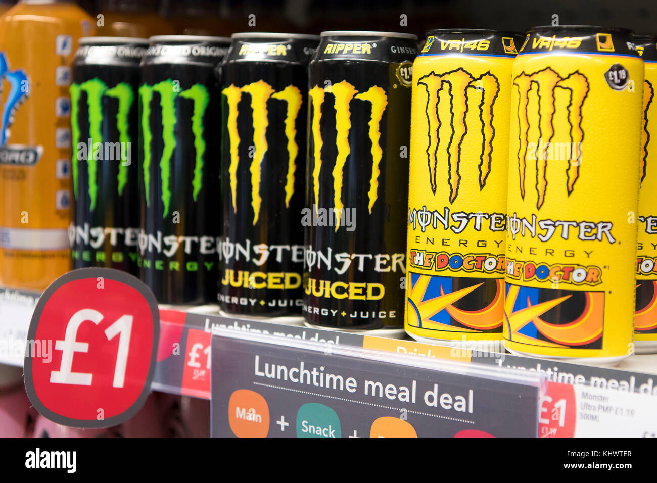 Cans of Monster energy drinks on display on sale on a shelf in a
