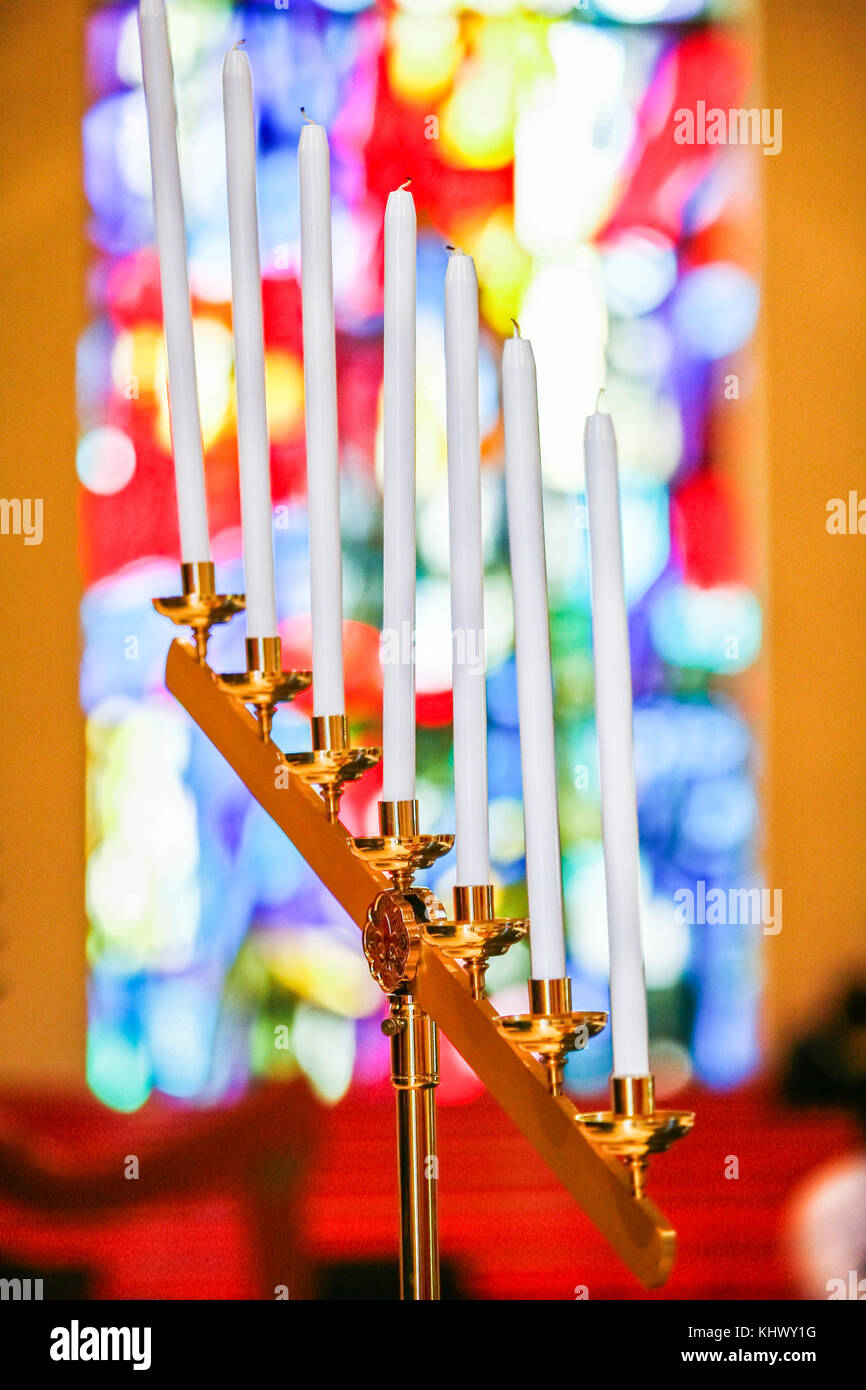 Seven burning white candles on candle holder with blurred colorful