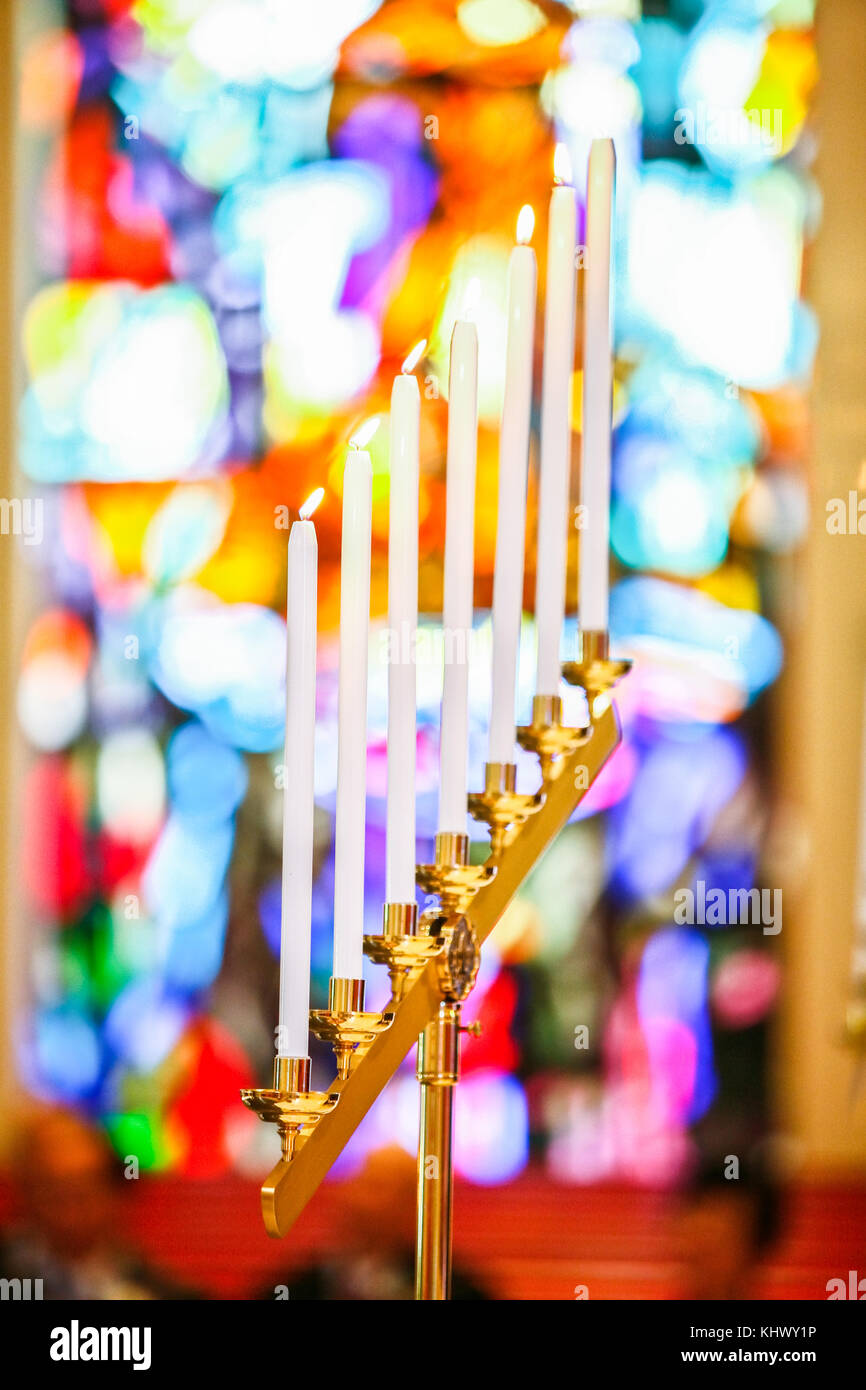 Seven burning white candles on candle holder with blurred colorful