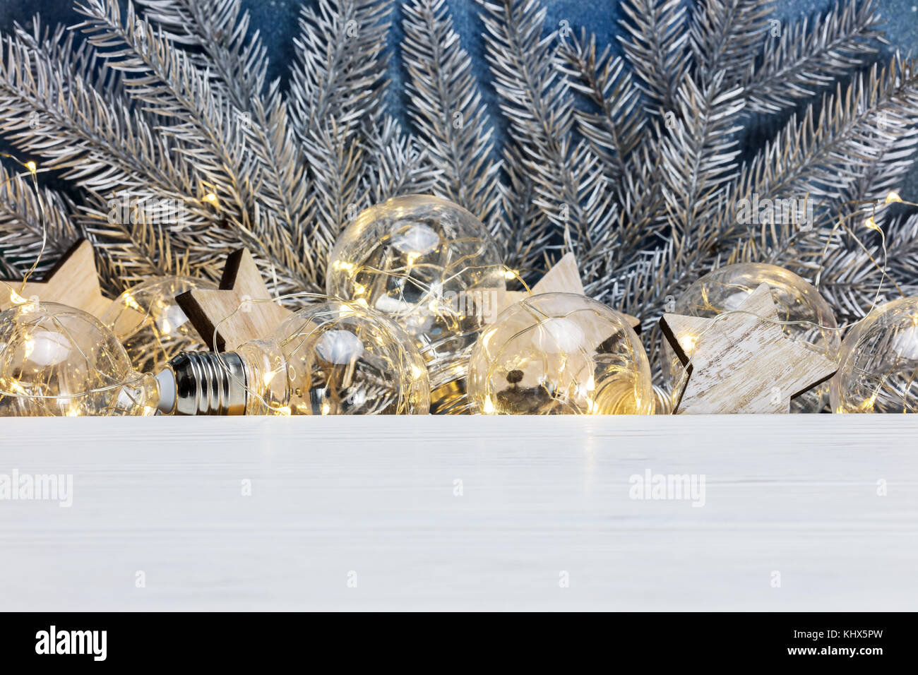 retro light garlands, silver christmas fir tree branches and wooden ...