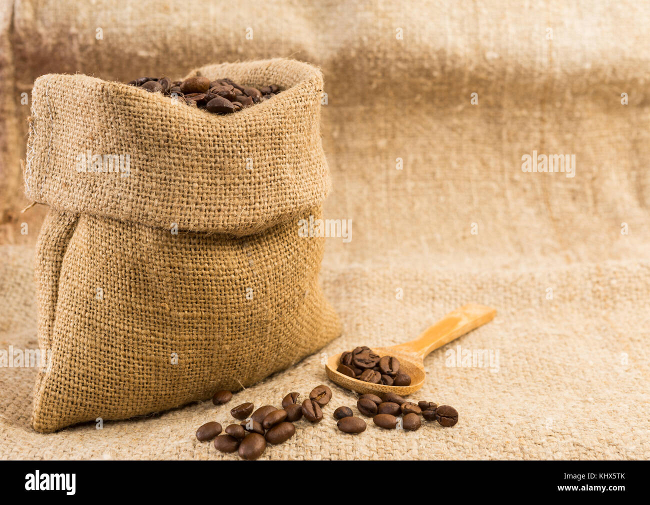 Jute bag of coffee with wooden spoon filled with roasted beans Stock