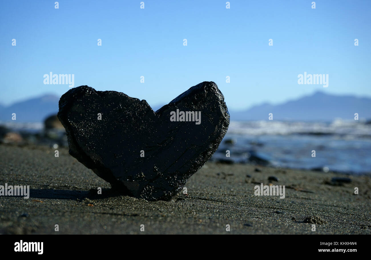 Piece of coal in heartshape on tidal beach sand, Cook Inlet, Kenai Peninsula, Alaska Stock Photo