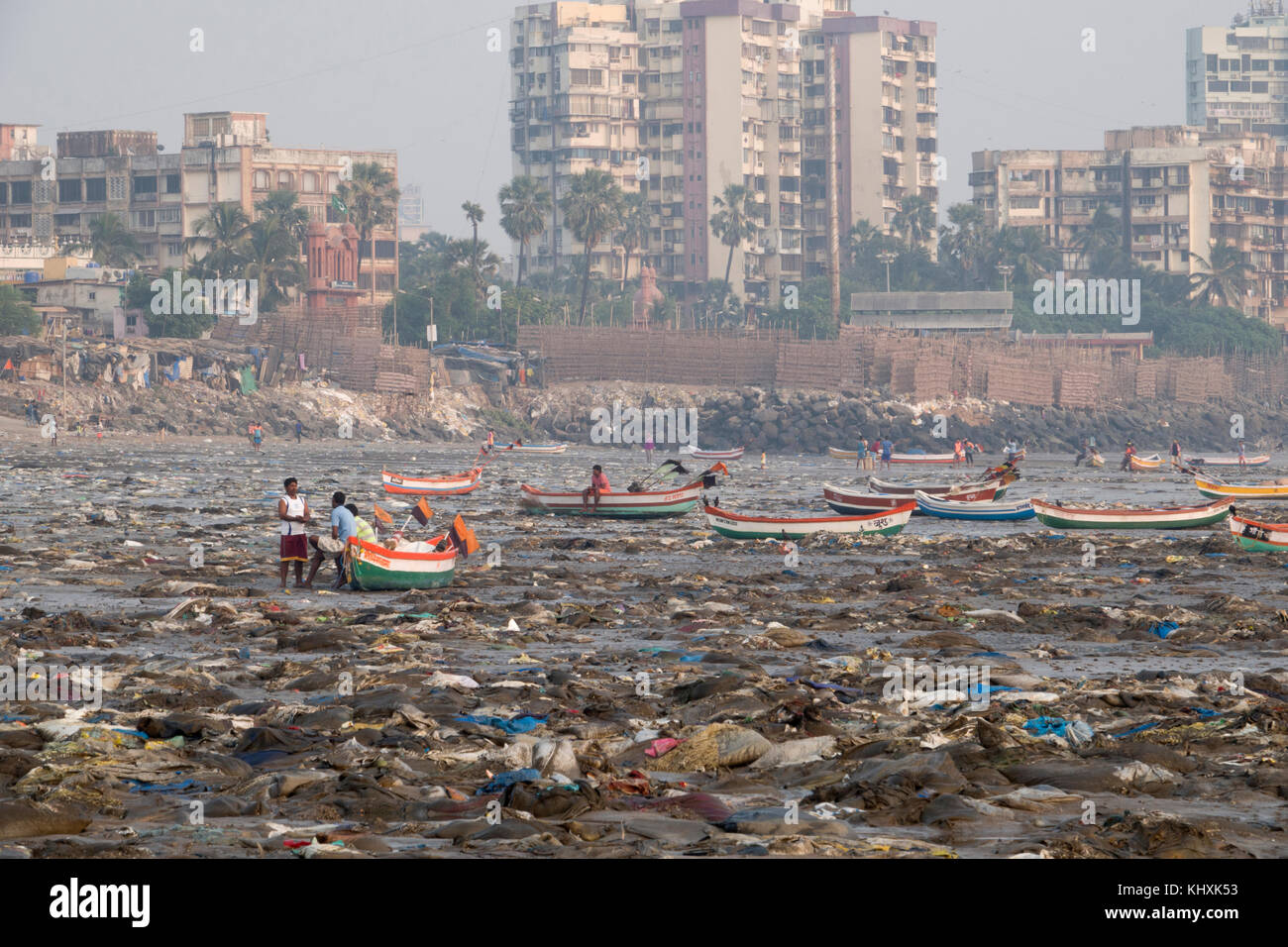 Small fishing boats surrounded by plastic garbage and other rubbish on Versova Beach, Mumbai Stock Photo
