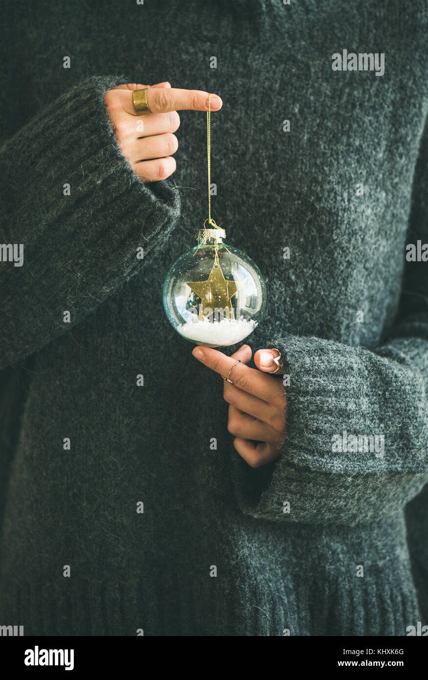 Woman in grey warm woolen sweater holding decorative glass ball Stock Photo