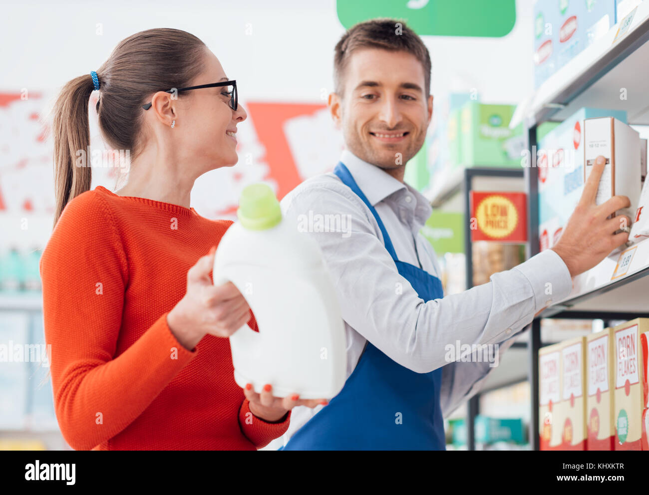 Professional supermarket clerk helping a customer, she is showing him a laundry detergent product Stock Photo
