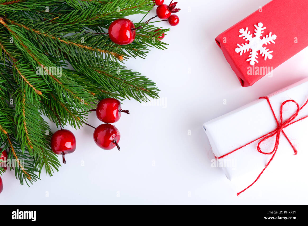 Green spruce branches decorated with berries and gift boxes on a white ...