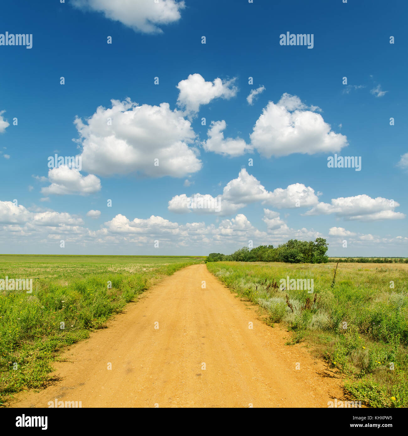 red dirty road in green fields under deep blue sky with clouds Stock ...
