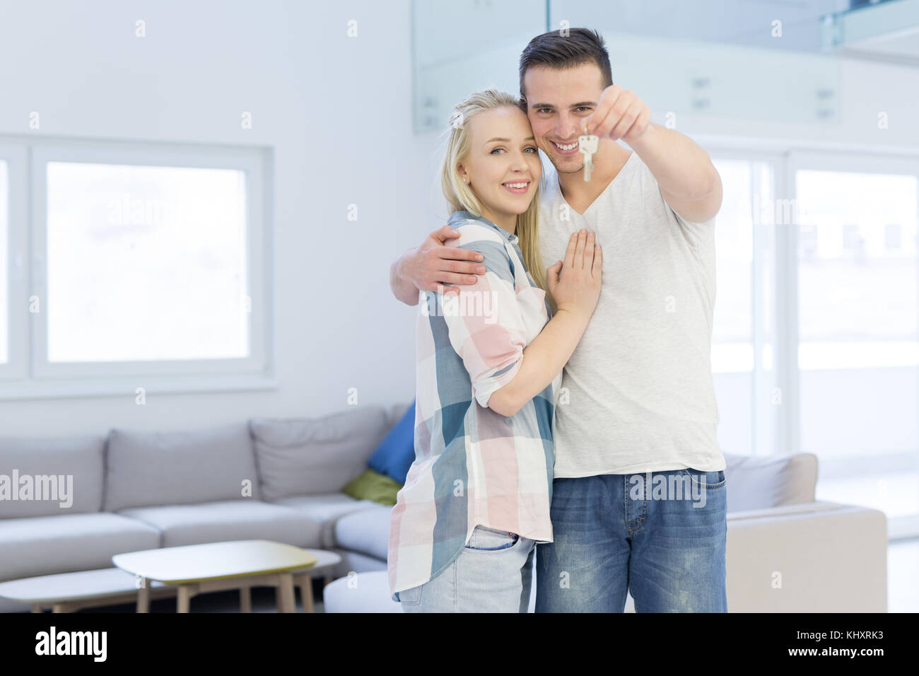 Happy smiling young couple hugging while showing a keys of their new ...