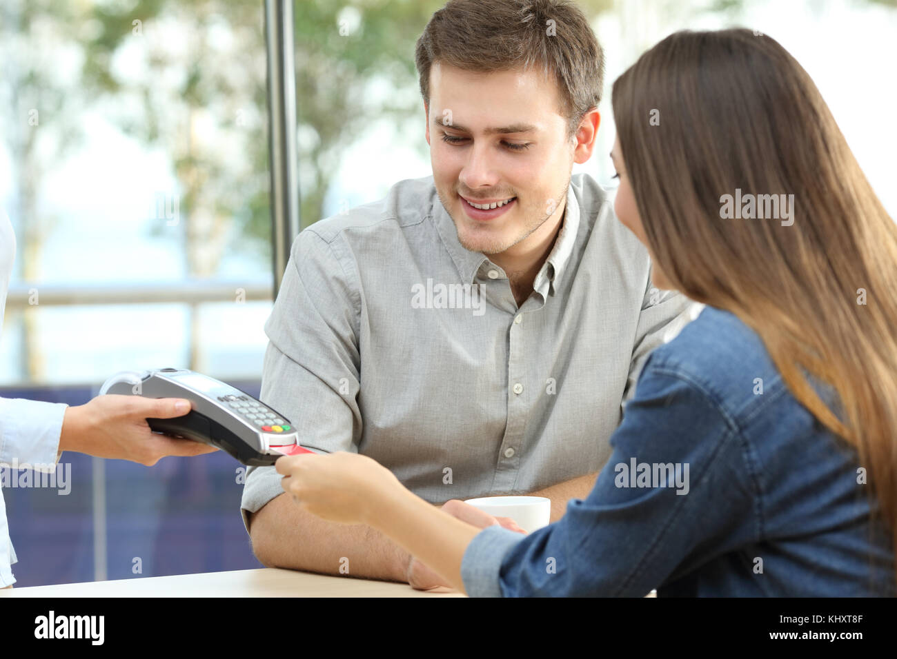 Happy couple paying with credit card in a bar interior Stock Photo