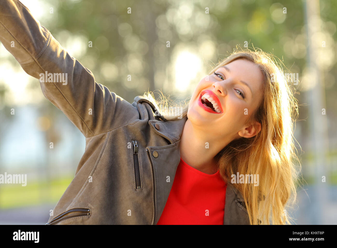 Portrait of a funny woman joking in a park and looking you at sunset Stock Photo