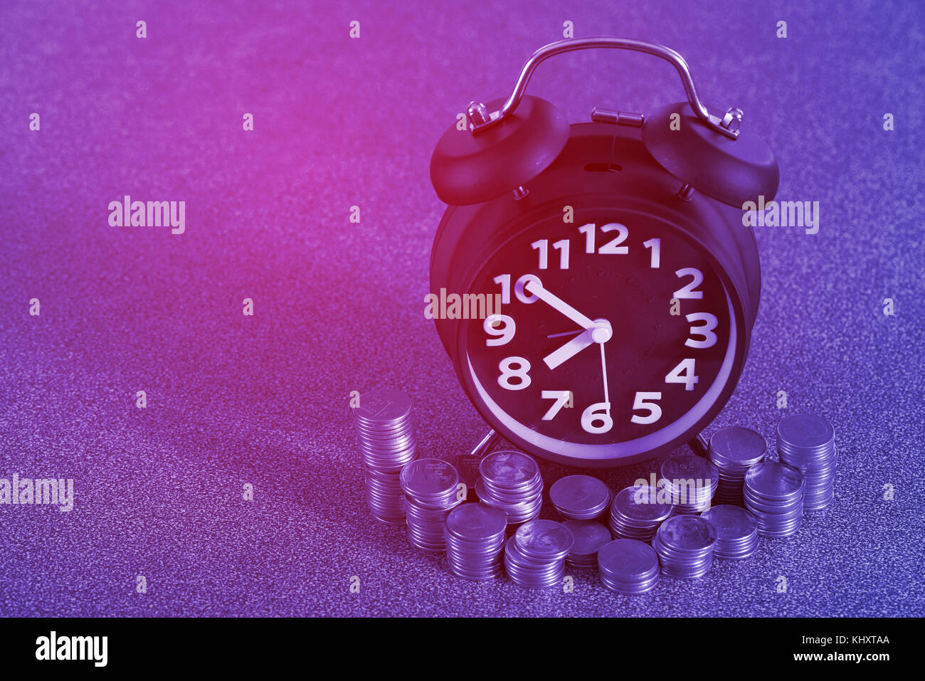 Alarm clock and step of coins stacks on working table, time for savings